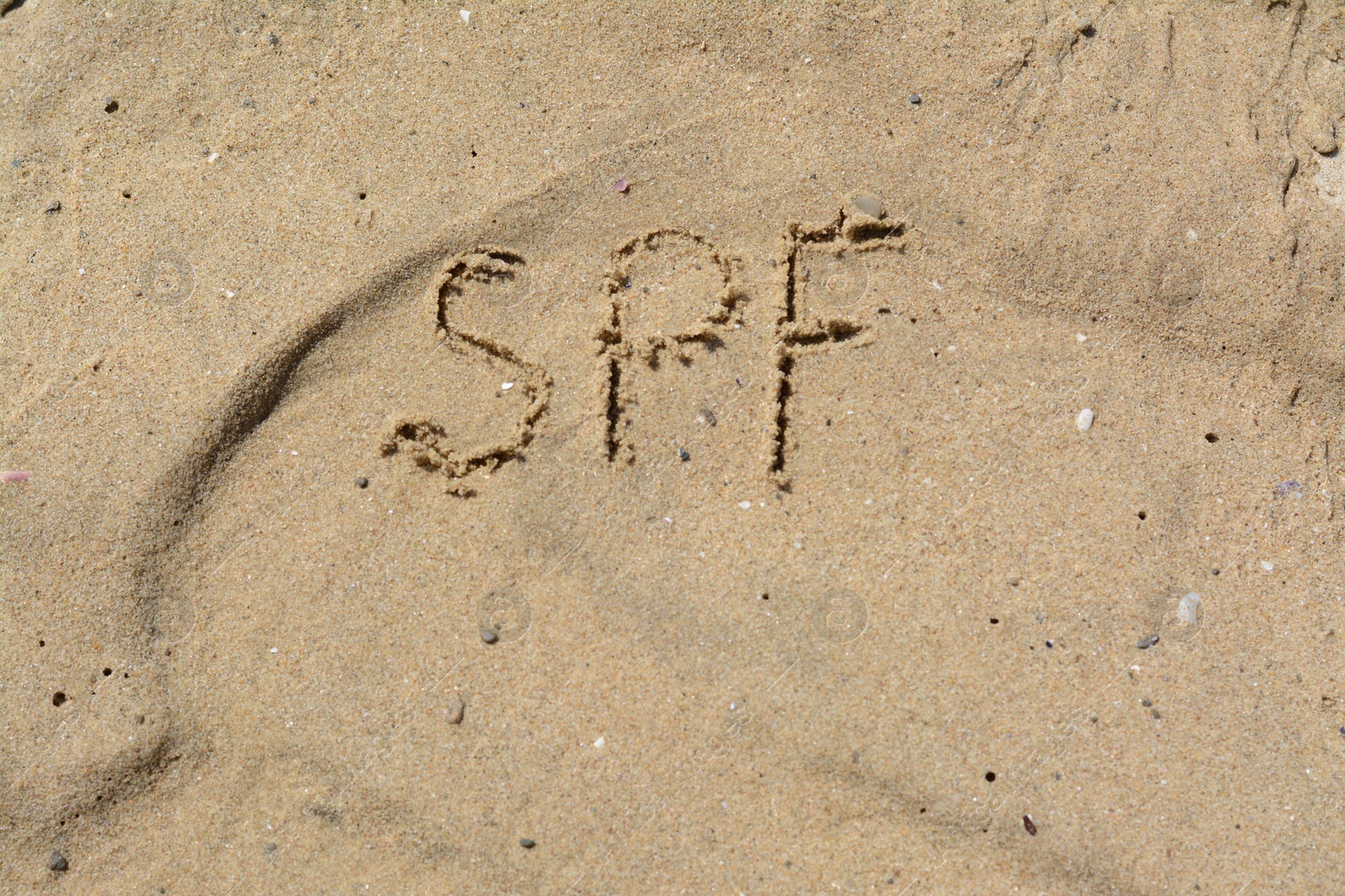 Photo of Abbreviation SPF written on sand at beach, top view. Space for text