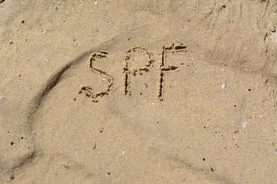 Photo of Abbreviation SPF written on sand at beach, top view. Space for text