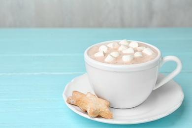 Photo of Composition with delicious cacao drink in cup on turquoise wooden background