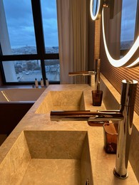 Photo of Modern sinks and faucets in hotel bathroom