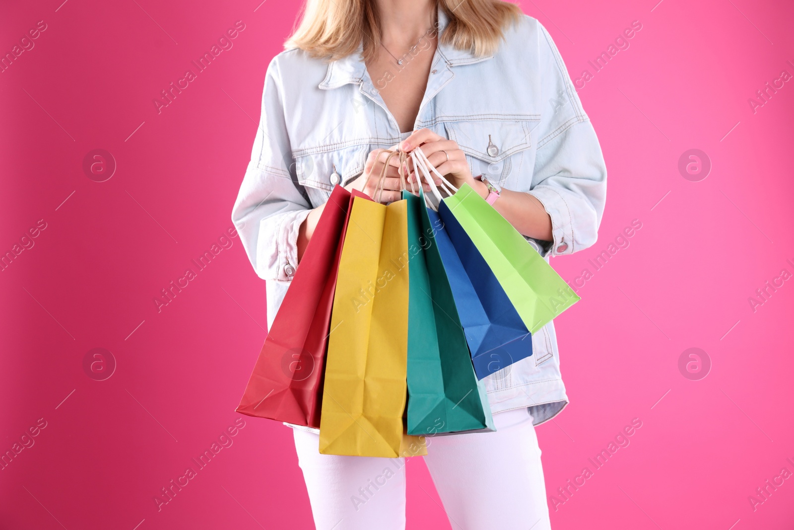 Photo of Young woman with shopping bags on color background, closeup