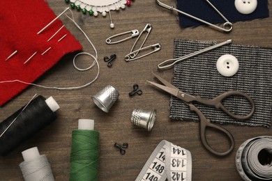 Photo of Flat lay composition with thimbles and different sewing tools on wooden table