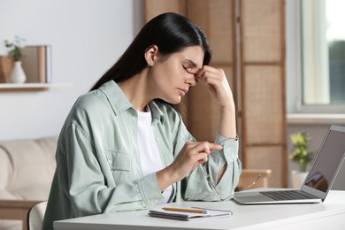 Photo of Young woman suffering from eyestrain at desk in office