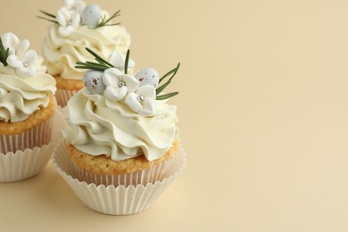 Photo of Tasty Easter cupcakes with vanilla cream on beige background, space for text