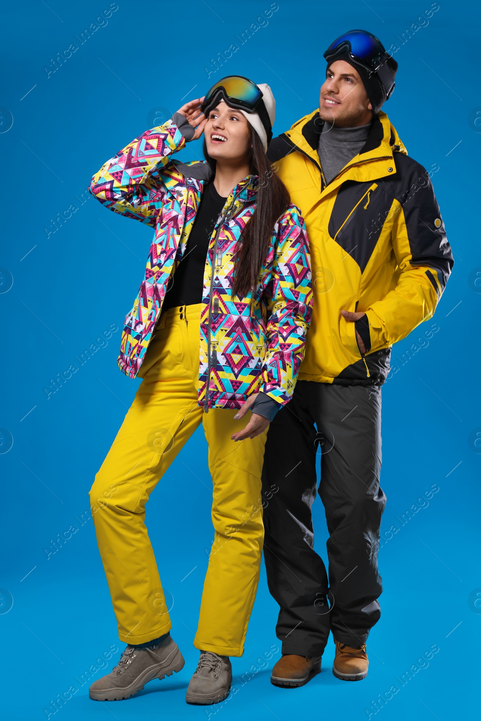 Photo of Couple wearing stylish winter sport clothes on light blue background