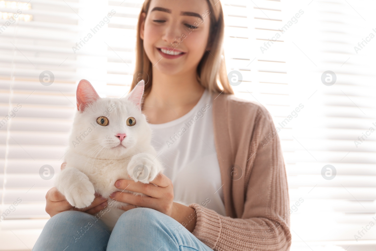 Photo of Young woman with her beautiful white cat at home. Fluffy pet