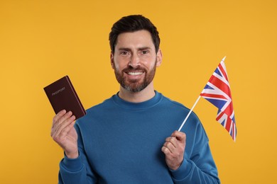 Photo of Immigration. Happy man with passport and flag of United Kingdom on orange background