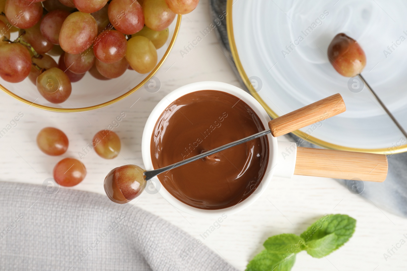 Photo of Flat lay composition with fondue pot and chocolate on white wooden table