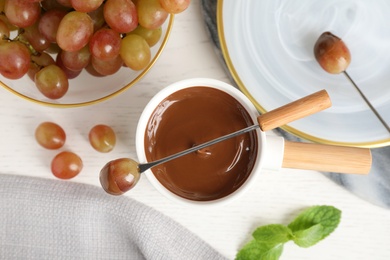 Photo of Flat lay composition with fondue pot and chocolate on white wooden table