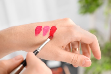 Woman testing and choosing lip gloss color on hand, closeup