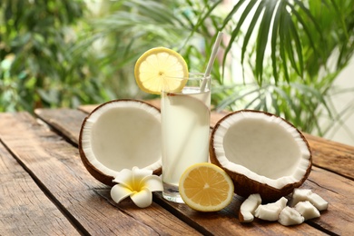 Photo of Composition with glass of coconut water and lemon on wooden table