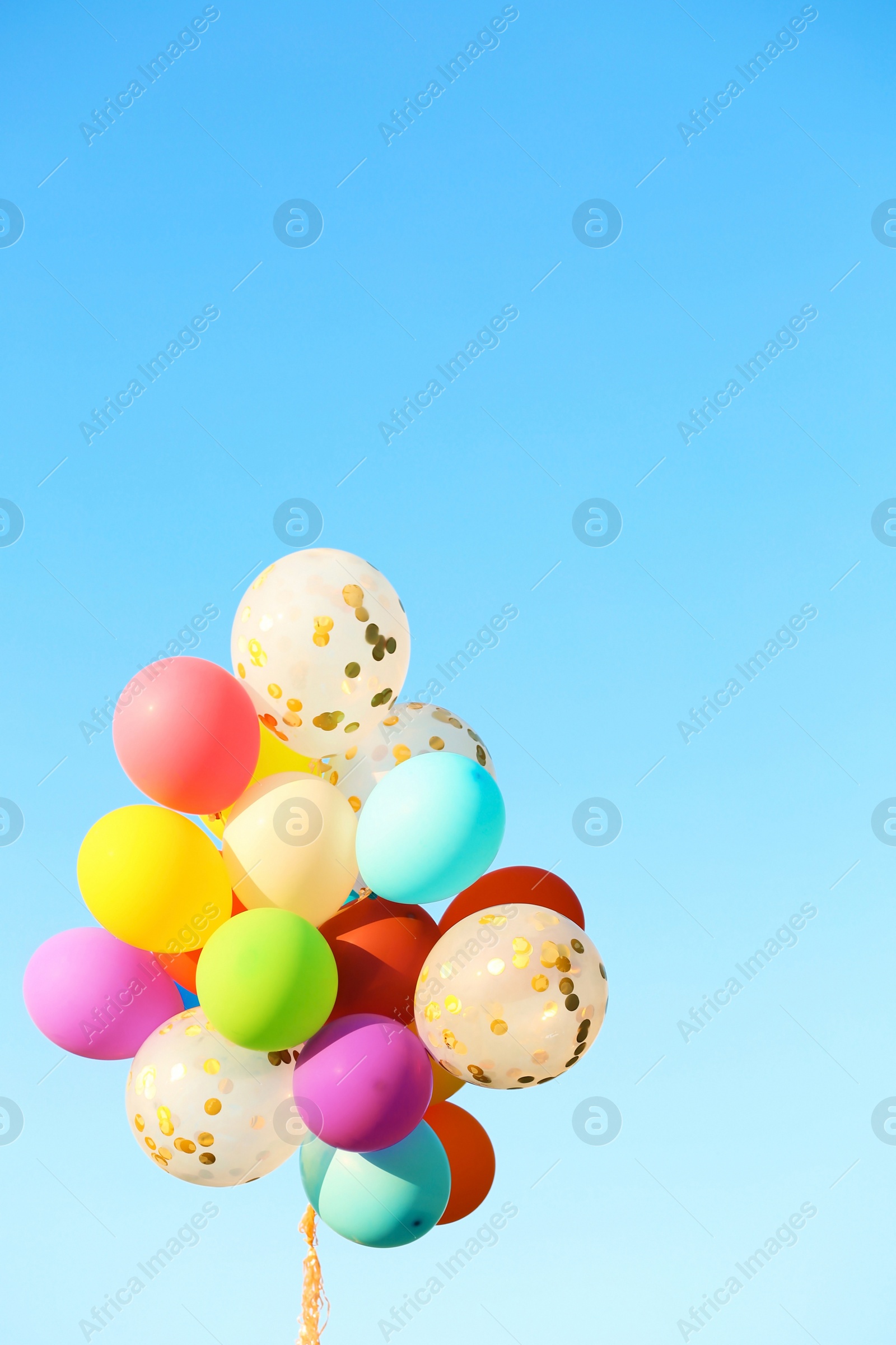 Photo of Many colorful balloons against blue sky on sunny day