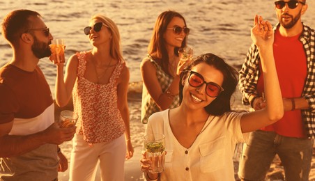 Image of Woman with friends having fun near river at summer party