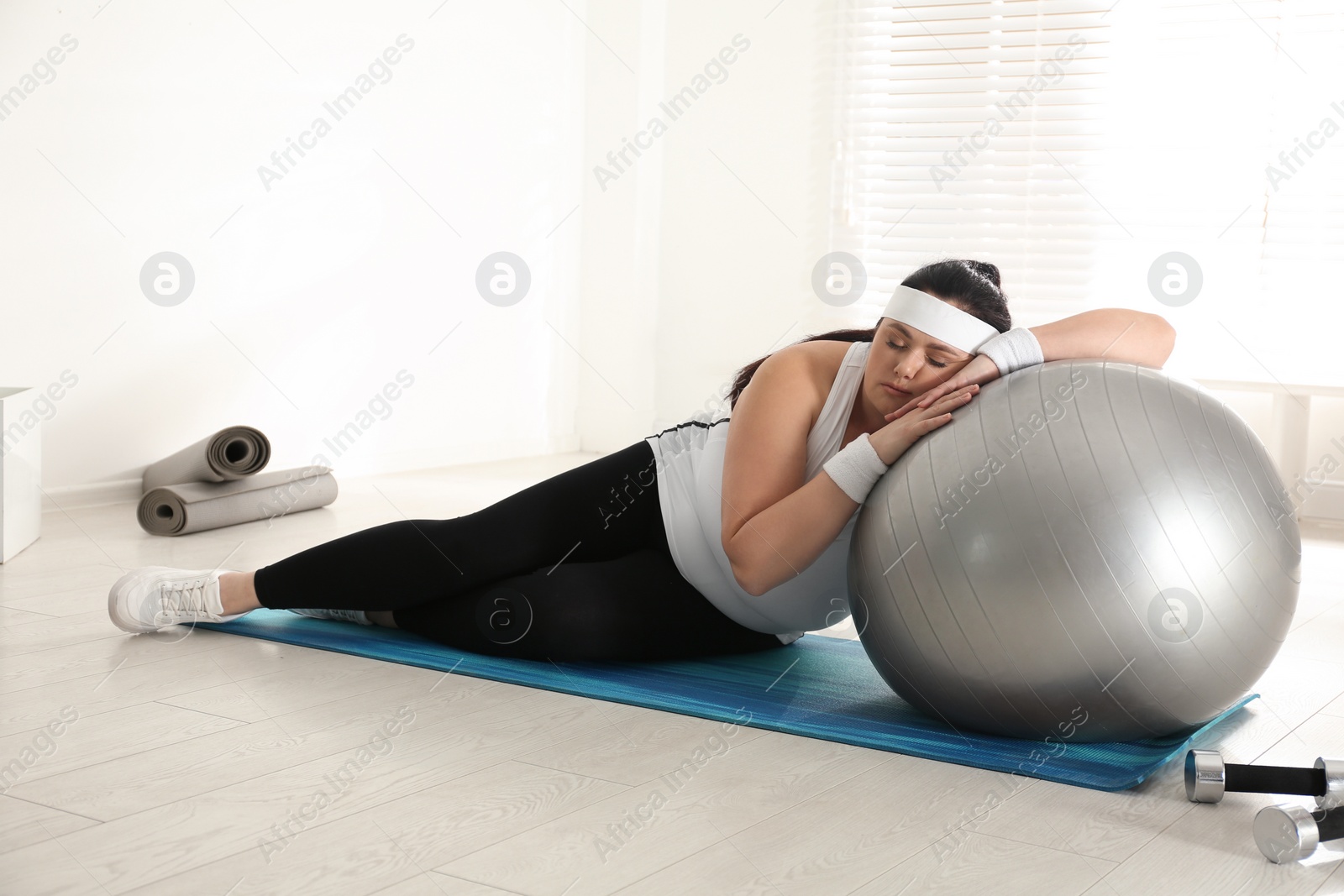 Photo of Lazy overweight woman leaning on fit ball instead of training at gym