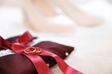 Decorative pillow with wedding rings on light background, closeup