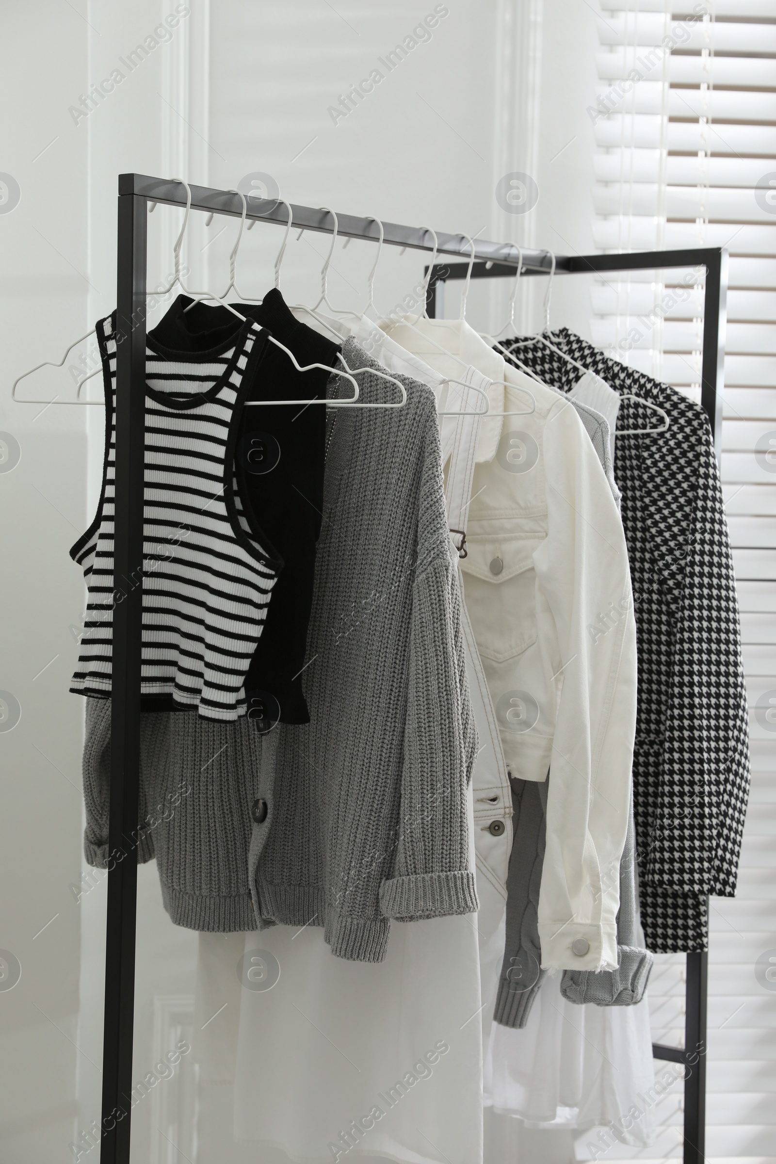 Photo of Rack with stylish women's clothes in dressing room. Interior design