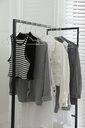 Photo of Rack with stylish women's clothes in dressing room. Interior design