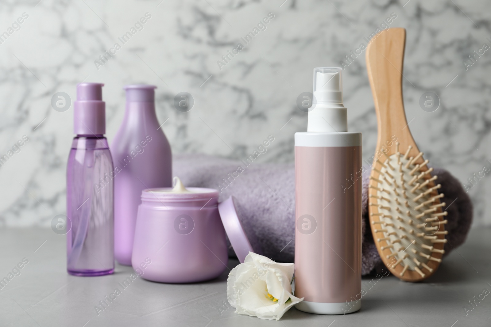 Photo of Different hair products, towel and brush on grey table