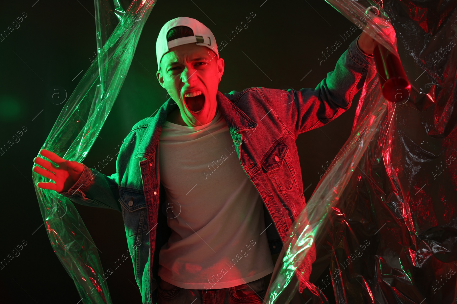 Photo of Young man with baseball bat on dark background in neon lights