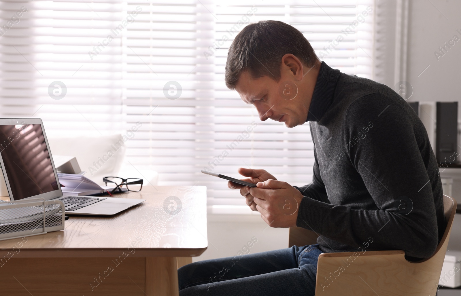 Photo of Man with bad posture using tablet in office