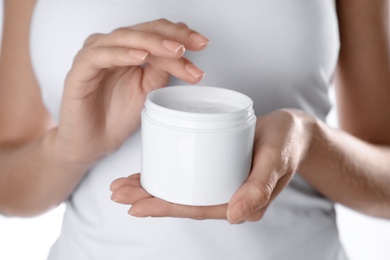 Photo of Woman with jar of moisturizing cream on white background, closeup