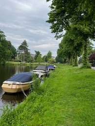 Photo of Beautiful view of city canal with moored boats surrounded by greenery
