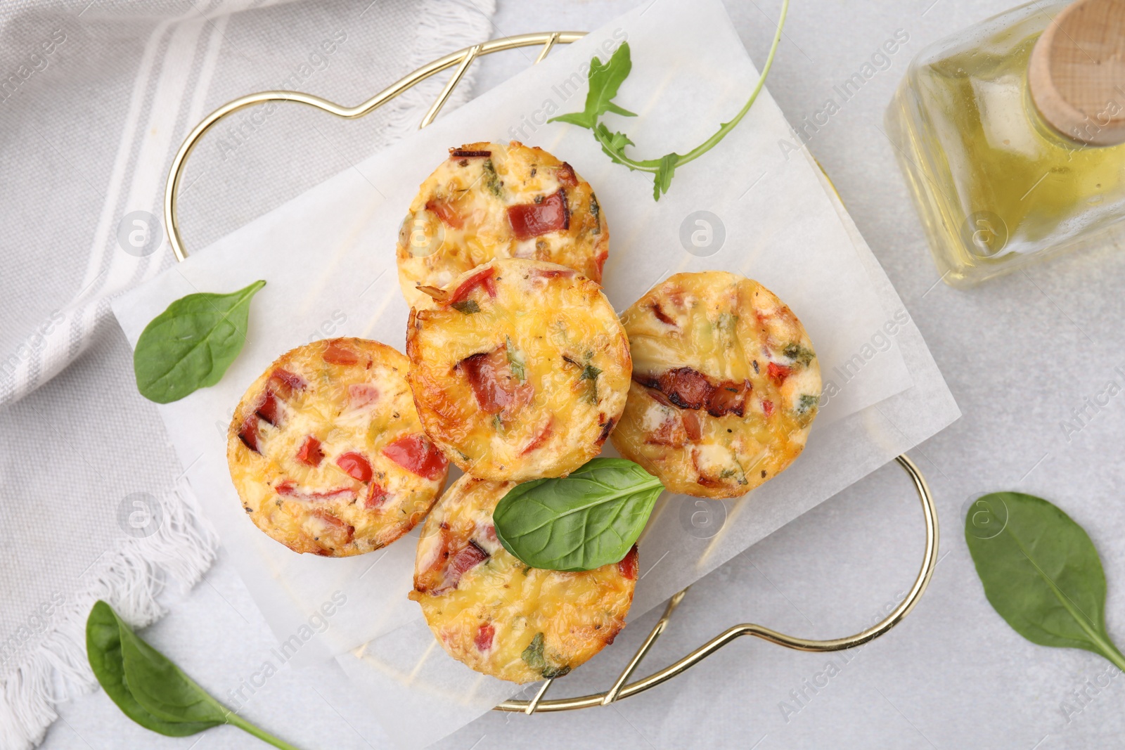 Photo of Freshly baked bacon and egg muffins with cheese on light gray table, flat lay