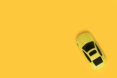 Photo of One bright car on yellow background, top view with space for text. Children`s toy