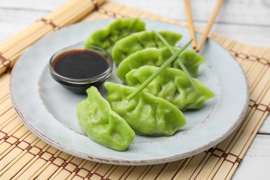 Delicious green dumplings (gyozas) and soy sauce on white table, closeup