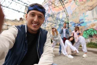 Photo of Man taking selfie with group of people outdoors, selective focus. Hip hop dancers