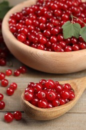 Photo of Ripe red currants and leaves on wooden table