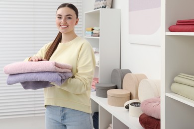 Photo of Smiling young woman holding towels in home textiles store. Space for text