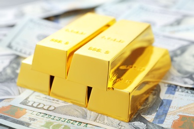 Photo of Precious shiny gold bars on dollar bills