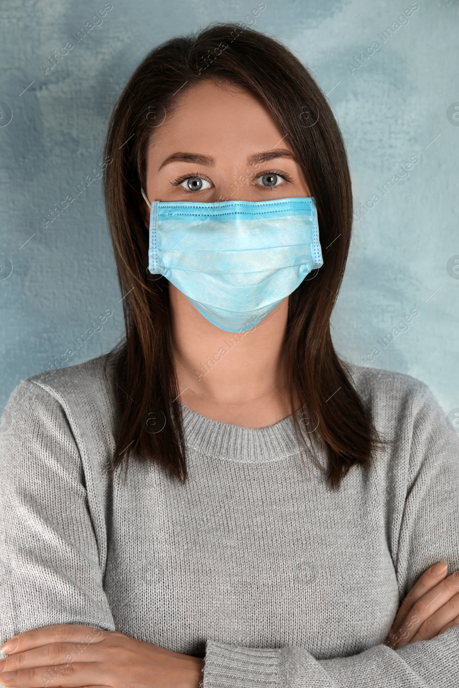 Photo of Woman with disposable mask on face against light blue background