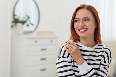 Portrait of beautiful smiling young woman. Happy lady with red hair at home. Space for text