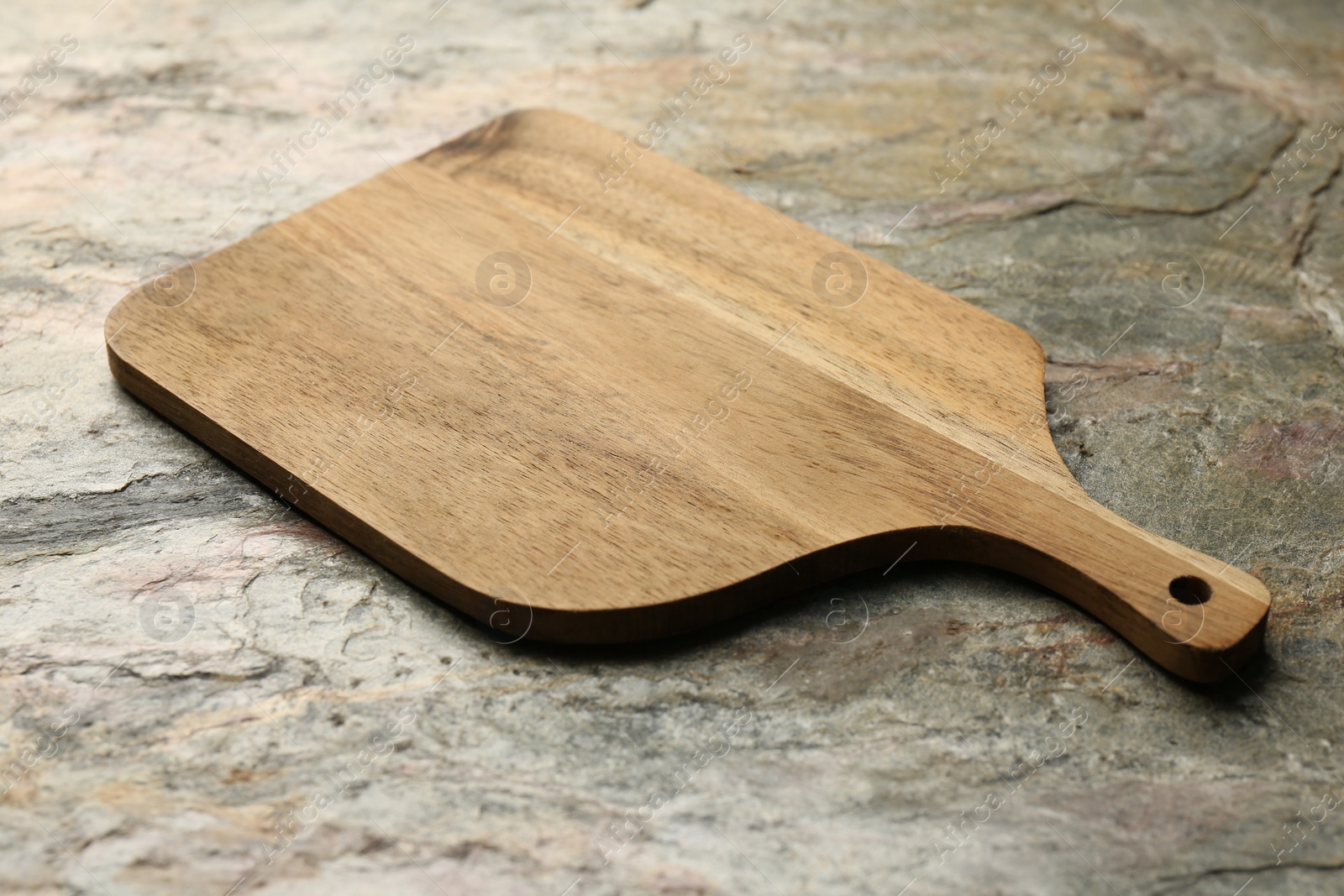 Photo of Wooden cutting board on textured table, closeup