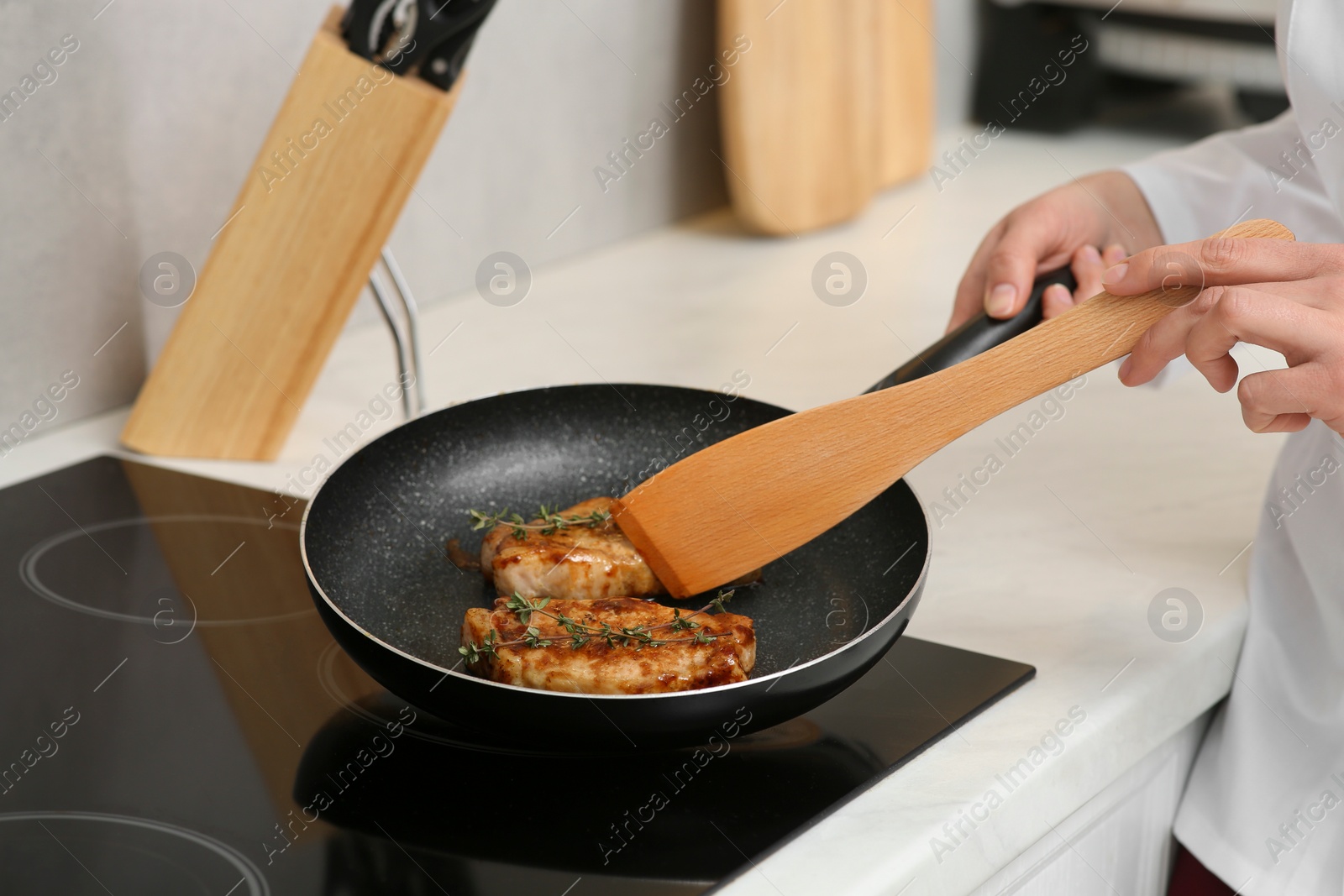 Photo of Chef cooking delicious meat with thyme in frying pan indoors, closeup