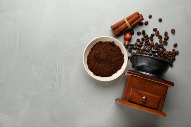 Vintage manual coffee grinder with beans and powder on light grey table, flat lay. Space for text