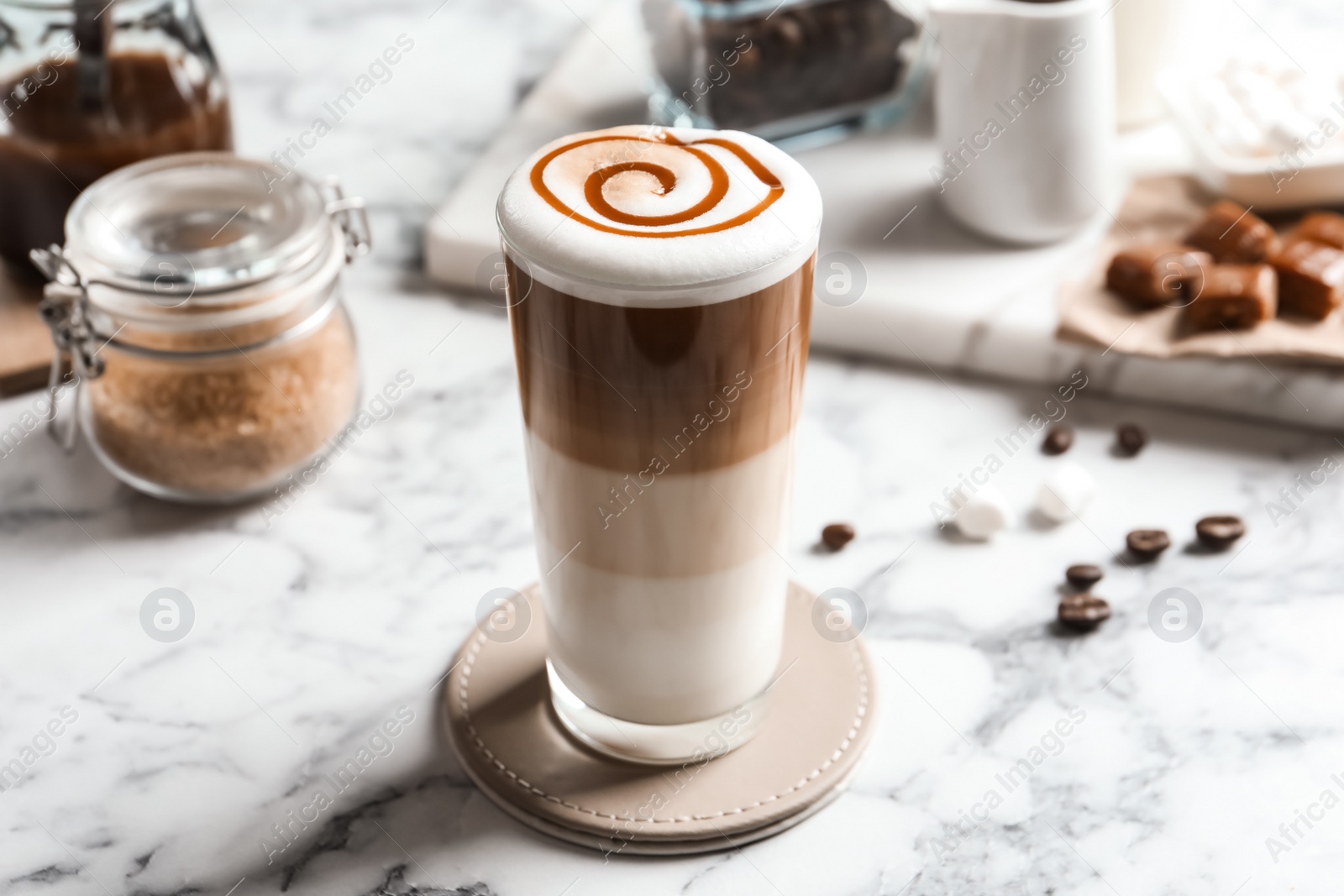 Photo of Glass with delicious caramel latte on table