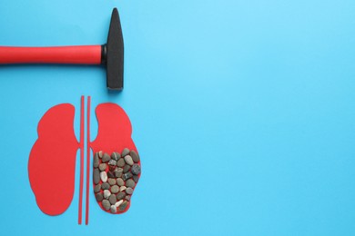 Paper cutout of kidneys with stones and hammer on light blue background, flat lay. Space for text