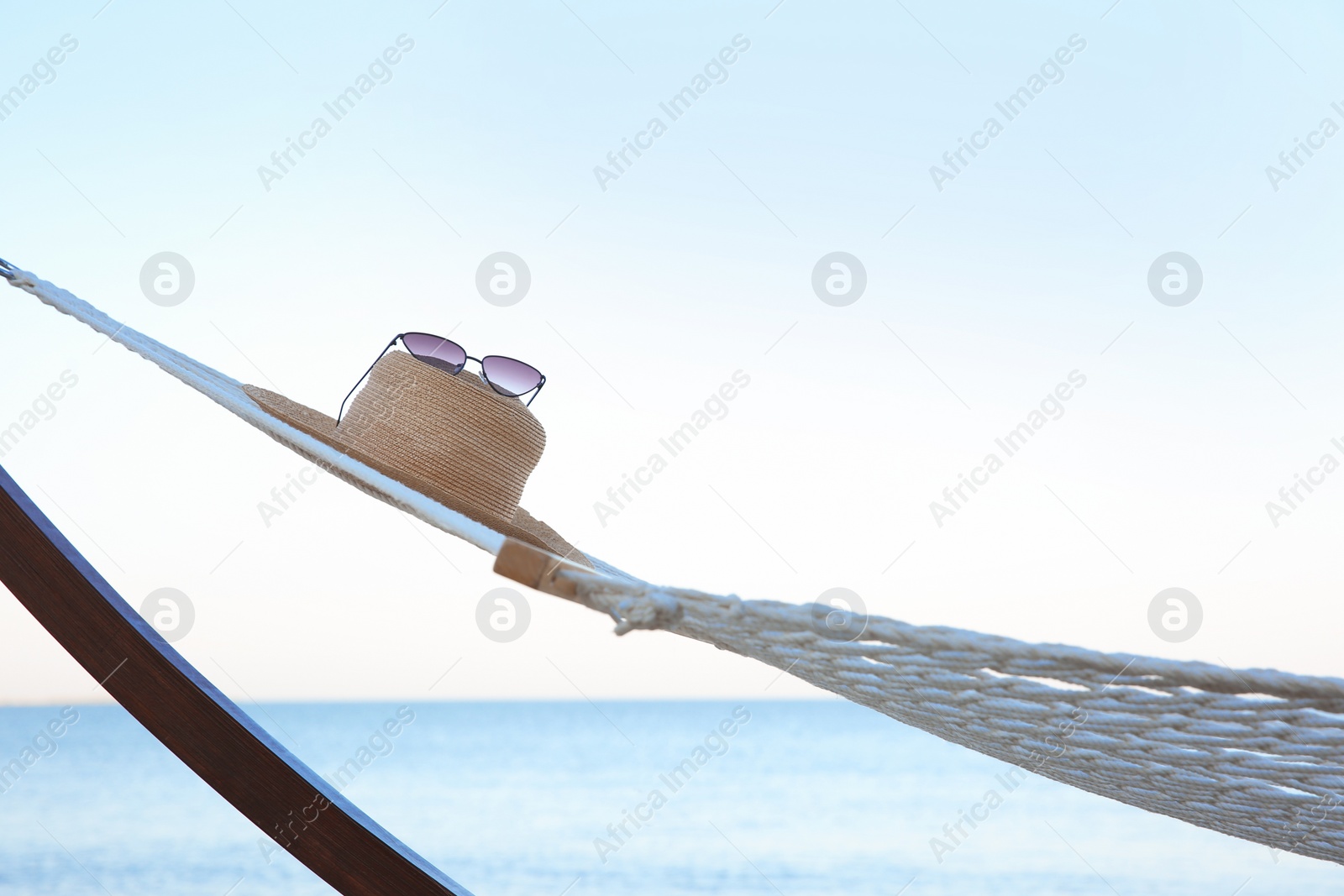 Photo of Comfortable hammock with straw hat and sunglasses at seaside