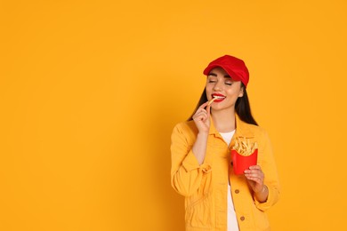 Photo of Beautiful young woman eating French fries on yellow background. Space for text