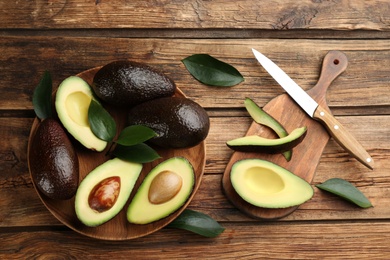 Photo of Whole and cut avocados on wooden table, flat lay