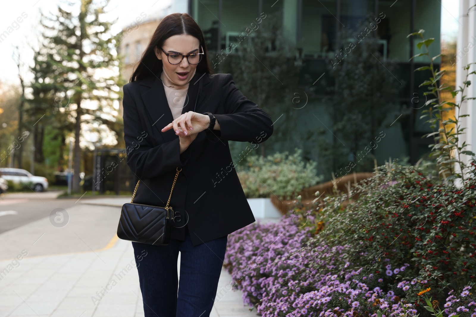 Photo of Emotional woman checking time on watch outdoors. Being late concept
