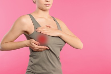 Image of Woman checking her breast on pink background, closeup