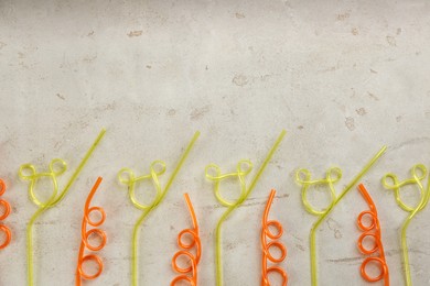 Colorful plastic drinking straws on grey stone table, flat lay. Space for text