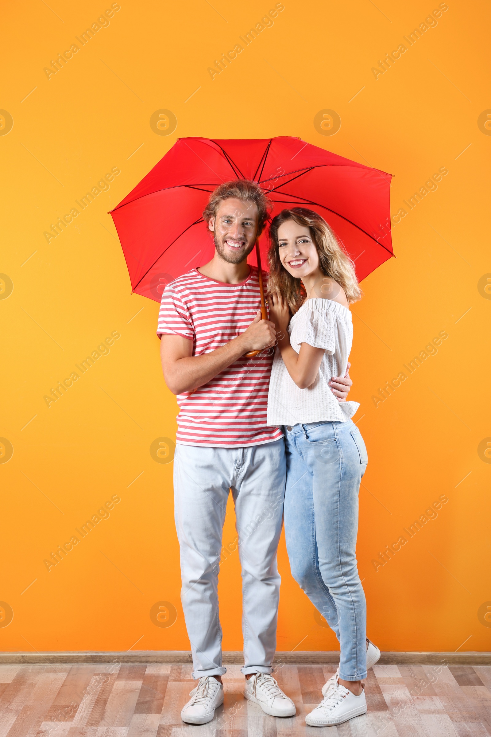 Photo of Couple with red umbrella near color wall