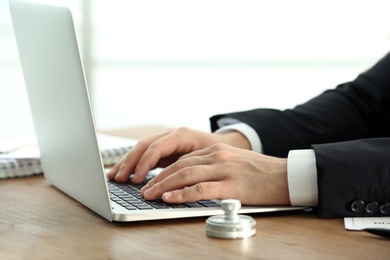 Male notary working with laptop at table, closeup