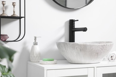 Different bath accessories and personal care products near sink on bathroom vanity