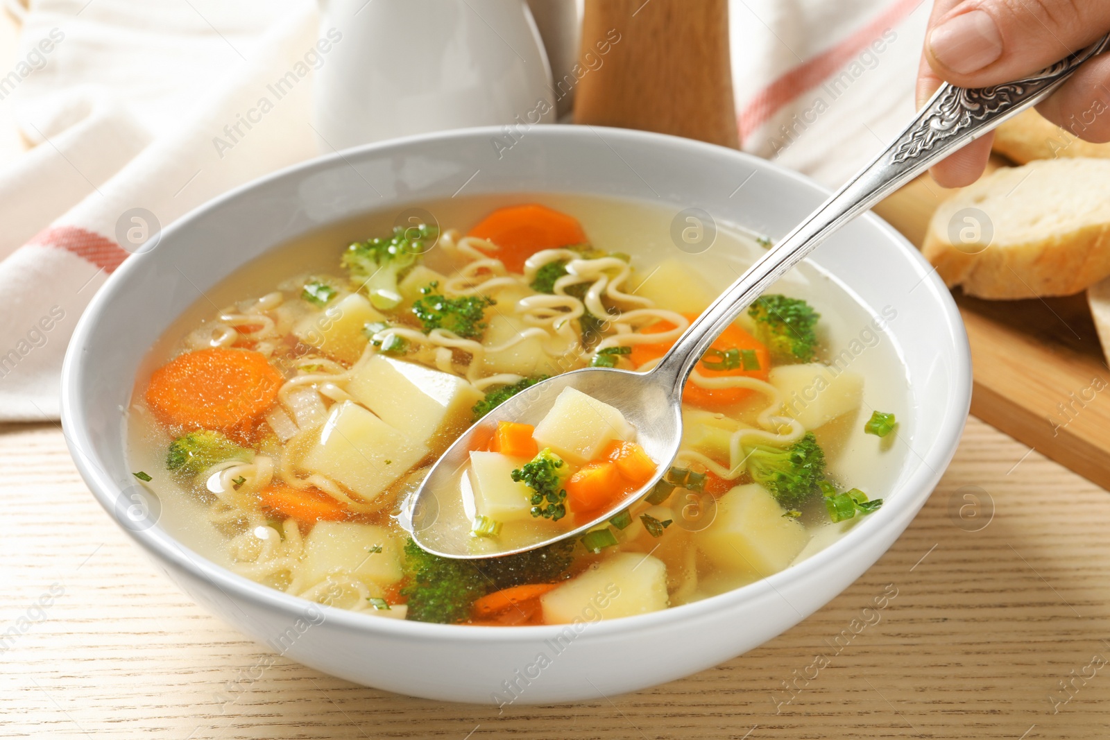 Photo of Woman eating fresh homemade vegetable soup at wooden table, closeup